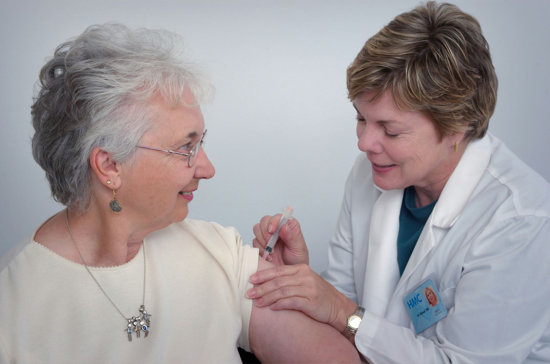 older woman receiving a vaccination from a clinician 