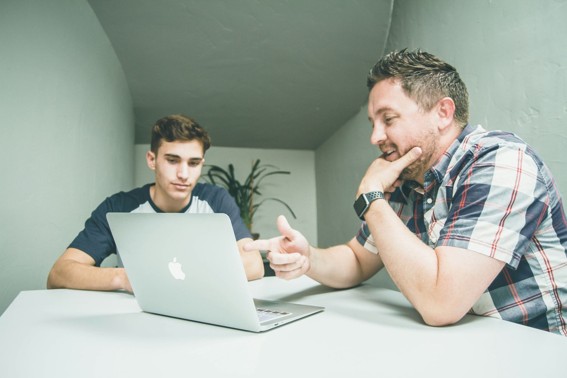 2 men talking looking at a laptop